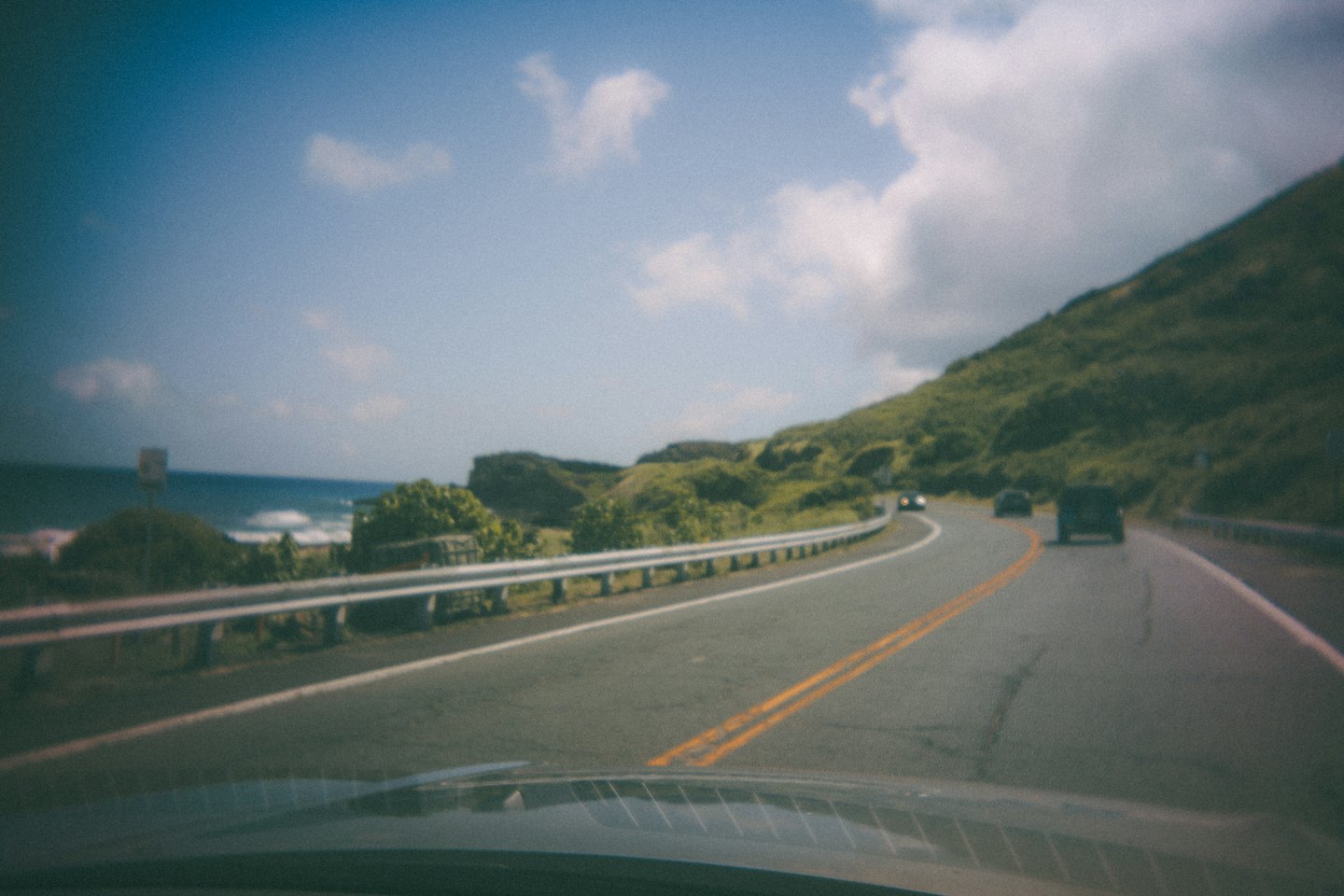 View of a winding coastal highway from a car dashboard.